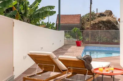 a patio with two chairs and a table and a pool at Vila Chu by An Island Apart in Ponta do Sol