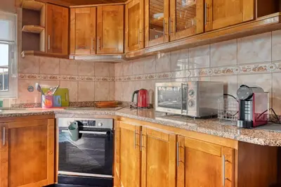 a kitchen with wooden cabinets and a microwave at Casa Primavera, a Home in Madeira in Ponta do Sol