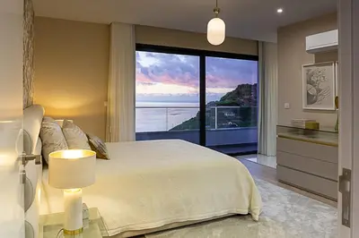 a bedroom with a large bed and a large window at Quinta do Feliz, a Home in Madeira in Ponta do Sol