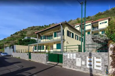 a yellow building with green doors on a hill at 2 Bedroom Apartment in Calheta in Arco da Calheta