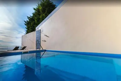 a swimming pool next to a white wall at 2 Bedroom Apartment in Calheta in Arco da Calheta