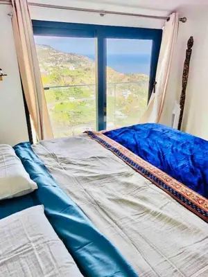 a bed in a room with a large window at Mar a Vista by Your Madeira Rentals in Ponta do Sol