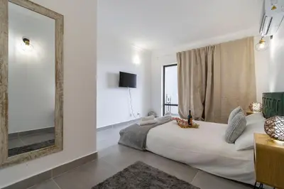 a bedroom with a large bed and a mirror at 3 Minutes TO THE BEACH, 2 BEDROOM AMAZING APT WITH BALCONY, BBQ GRILL AND POOL in Sagres