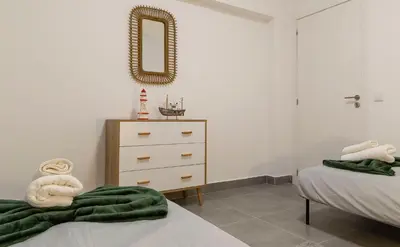 a bedroom with two beds and a dresser and a mirror at 3 Minutes TO THE BEACH, 2 BEDROOM AMAZING APT WITH BALCONY, BBQ GRILL AND POOL in Sagres