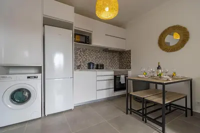 a kitchen with a washing machine and a table at 3 Minutes TO THE BEACH, 2 BEDROOM AMAZING APT WITH BALCONY, BBQ GRILL AND POOL in Sagres