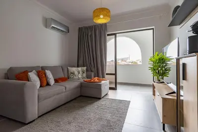 a living room with a couch and a large window at 3 Minutes TO THE BEACH, 2 BEDROOM AMAZING APT WITH BALCONY, BBQ GRILL AND POOL in Sagres