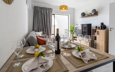 a dining room table with a bottle of wine and glasses at 3 Minutes TO THE BEACH, 2 BEDROOM AMAZING APT WITH BALCONY, BBQ GRILL AND POOL in Sagres