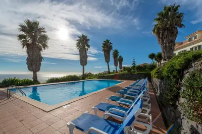 a row of blue lounge chairs next to a swimming pool at Quinta Alegre in Calheta