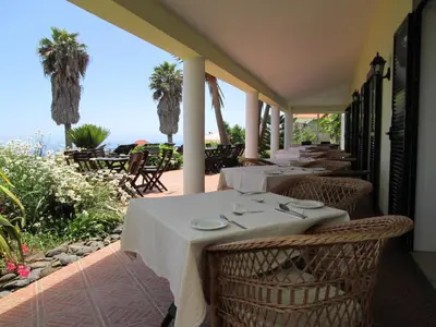 a row of tables on a balcony with palm trees at Quinta Alegre in Calheta