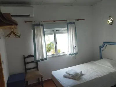 a bedroom with a bed and a chair and a window at Casa Sarguito in Sagres