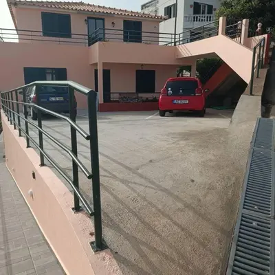 a red car parked in a parking lot next to a house at Casa Bela Vista Studio 2 in Ribeira Brava