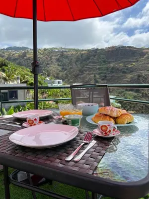 a table with plates of food and an umbrella at Pana House in Calheta