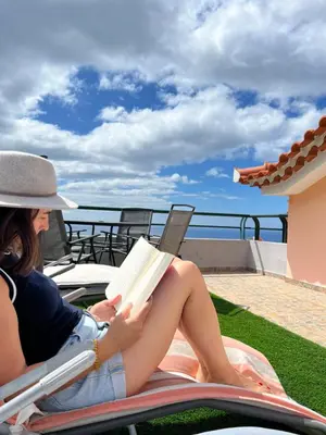 a woman sitting in a chair reading a book at Pana House in Calheta