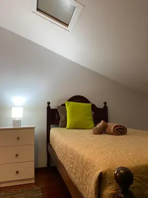 a bedroom with a bed with a green pillow and a dresser at Pana House in Calheta