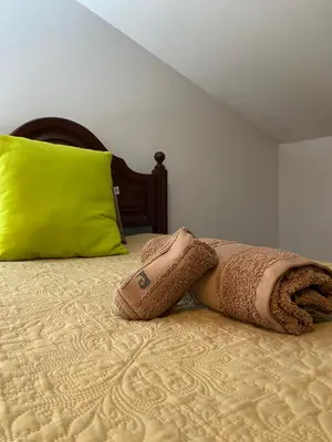 a blanket laying on top of a bed with a green pillow at Pana House in Calheta
