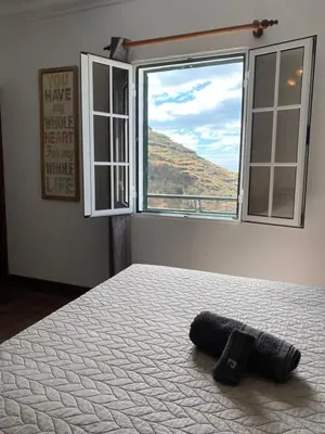 a bed in a room with a window and a remote control at Pana House in Calheta