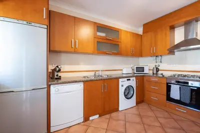 a kitchen with wooden cabinets and a washer and dryer at Porto de Mos 86 by Destination Algarve in Lagos