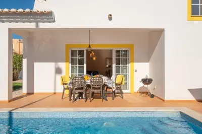 a dining table and chairs next to a swimming pool at Porto de Mos 86 by Destination Algarve in Lagos