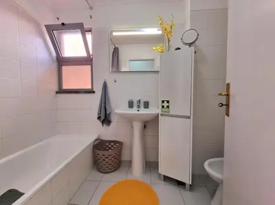 a white bathroom with a sink and a tub and a sink at Junto ao Mar - Apartamento T1 in Santa Cruz