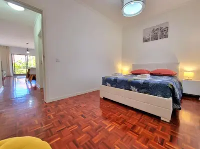 a bedroom with a bed and a wooden floor at Junto ao Mar - Apartamento T1 in Santa Cruz