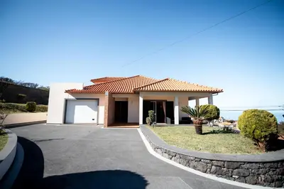 a small white house with a driveway at Brisas do Atlántico in Porto Moniz