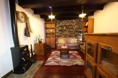 a living room with a stove and a couch at Casa do Ribeirinho in Porto Moniz