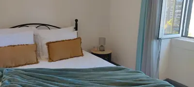 a bed with a blue blanket and a window at Casa das Vistas in Porto Moniz