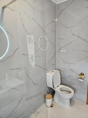 a bathroom with a toilet and a marble wall at Studio no centro do Funchal in Funchal