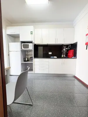a kitchen with white cabinets and a white chair at LIDO CASA BRANCA in Funchal