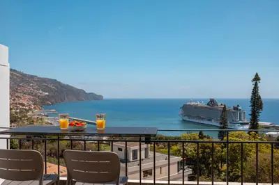 a balcony with a table and chairs and a cruise ship at Jasmineiro Mar - Ocean View Studio in Funchal