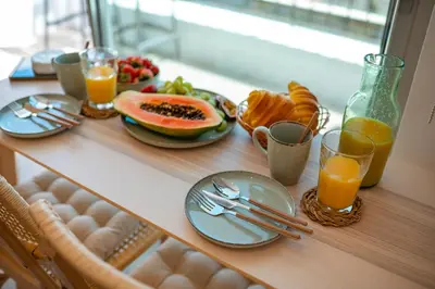 a table with plates of food and glasses of orange juice at Jasmineiro Mar - Ocean View Studio in Funchal