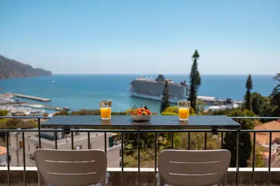 a table with two glasses of orange juice and a bowl of fruit at Jasmineiro Serra - Ocean View Studio in Funchal