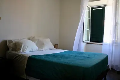 a bedroom with a bed with a green blanket and a window at Mountain View Villa in São Vicente