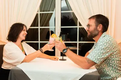 a man and a woman sitting at a table with drinks at BIO Hotel - Hotel Quinta da Serra in Estreito de Câmara de Lobos