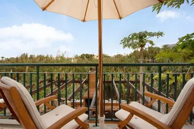 a balcony with two chairs and an umbrella at Energia Dourada - Porto Santo in Porto Santo