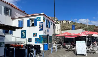 a patio with tables and umbrellas and a building at Lua do Mar in Caniço