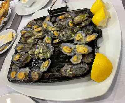 a plate of food with oysters and lemons on a table at Lua do Mar in Caniço
