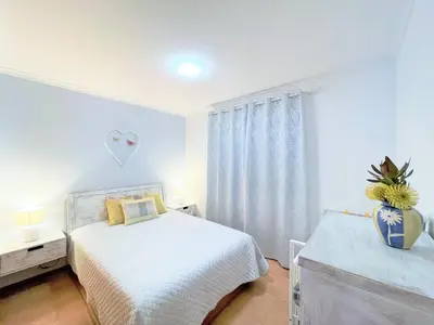a white bedroom with a bed and a vase at Lua do Mar in Caniço