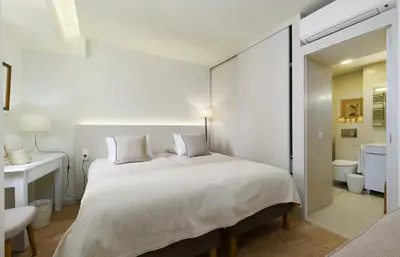a bedroom with a large white bed and a bathroom at Apartamentos do Mar - Pikis Flat in Funchal