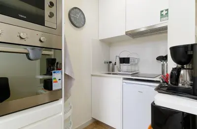 a kitchen with white cabinets and a clock on the wall at Apartamentos do Mar - Pikis Flat in Funchal