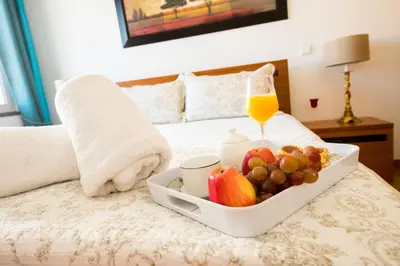 a tray of fruit on a bed with a glass of orange juice at Sunrise Apartment in Caniço