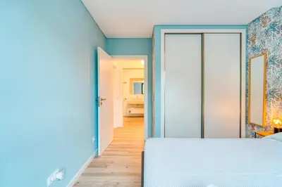 a bedroom with a white bed and a blue wall at Vista Verde Apartment by Amazing Madeira in Funchal