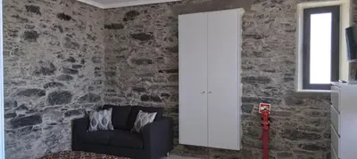 a living room with a chair and a stone wall at Paradise Santo Amaro II in Ponta do Sol