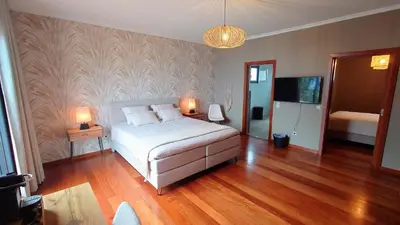 a bedroom with a bed and two lamps and a television at Casa do Mundo Madeira in Gaula