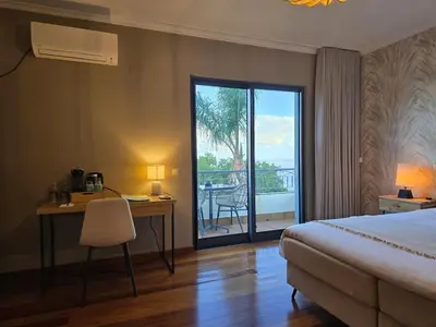a hotel room with a bed and a desk and a balcony at Casa do Mundo Madeira in Gaula