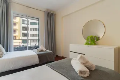 a bedroom with two beds and a mirror and a window at Gilda Apartment by Atlantic Holiday in Funchal