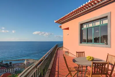 a balcony with a table and chairs and the ocean at Casa Coelho in Ponta do Sol