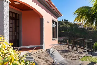 a house with a balcony with a table and chairs at Casa Coelho in Ponta do Sol
