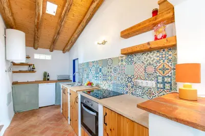 a kitchen with wooden cabinets and a tile wall at Da Casa Sesta in Sagres