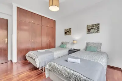 a bedroom with two beds and a wooden cabinet at Apartamento São João in Funchal